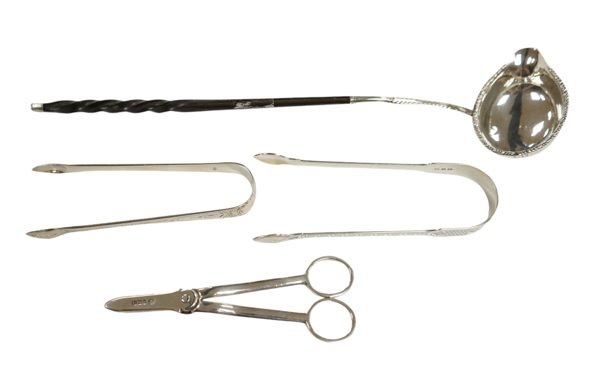 A pair of George V silver grape scissors, by William Hutton & Sons, two pairs of silver sugar tongs and a Georgian silver punch ladle. Condition - poor to fair